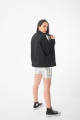 Campera de jean negra con detalles de cuero sintético plateado en la parte superior y tachas plateadas en los hombros.