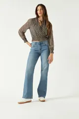 Blusa de manga larga con estampado floral pequeño sobre fondo oscuro. Presenta escote en V con lazo para anudar, cintura con frunce elástico y puños ajustados.