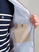 Campera Harrington color beige, con cuello alto abotonado, cierre frontal completo y bolsillos laterales con solapa y botones a presión. Puños y cintura elastizados de rib.