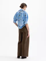 Pantalon de corte recto y tiro alto en color marron, con detalle de bordado en pedreria dorada sobre el frente. Presenta cierre frontal con botones y bolsillos laterales.