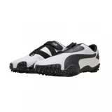 Championes Puma modelo Mostro Perforated, de diseño bajo con exterior de cuero perforado en color blanco y detalles en negro. Presenta una suela distintiva con relieve de tachones y cierre de velcro en el empeine.
