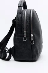Mochila negra de cuero sintético texturizado, con doble compartimento principal con cierre metálico, bolsillos laterales y manija superior. Incluye correas regulables.