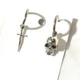 Par de aros tipo argolla de acero inoxidable con dijes colgantes asimétricos: uno con forma de daga y otro con forma de calavera.