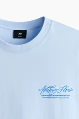 Remera celeste de corte holgado, con cuello redondo y diseño estampado en el pecho.