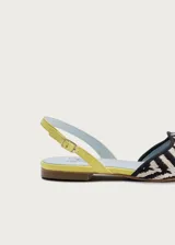 Ballerinas planas destalonadas de inspiración artesanal, con exterior en rafia trenzada con patrón en zigzag blanco y negro, y talón en napa color amarillo lima. Cuentan con una correa ajustable en el talón con hebilla dorada y una gran borla decorativa de flecos en el empeine.