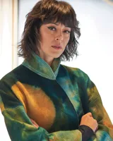 Tapado de lana merino afieltrada con teñido artesanal tie dye en tonos verdes y ocres. Tiene cuello alto, cierre cruzado asimétrico con broches, bolsillos laterales y corte holgado.