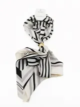 Pañuelo cuadrado de tela ligera color negro con estampado de lunares blancos y borde con franja blanca. Incluye un anillo metálico dorado para sujetar y estilizar el pañuelo.