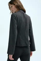 Top entallado en punto fino color gris melange, con cuello alto, mangas largas acampanadas y pinzas con efecto moldeador en la cintura. Cuenta con abertura de cerradura con botón en la parte posterior.