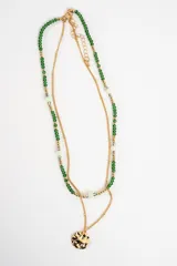 Collar doble compuesto por una cadena fina dorada con dije circular texturizado y otra tira de cuentas verdes y doradas con detalles translúcidos.