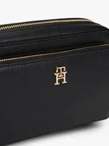 Cartera tipo bandolera de Tommy Hilfiger, color negro con acabado granulado. Presenta cierre de cremallera, bolsillo frontal con cierre, insignia del monograma TH en metal dorado y correa extraíble.