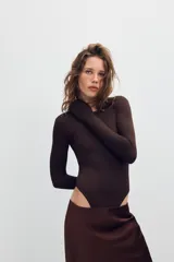 Body de poliamida con cuello redondo y manga larga. Presenta un diseño ajustado con cierre de botones a presión en la parte inferior.
