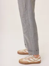 Pantalón de vestir gris con patrón de espiga, corte ancho y tiro alto. Presenta costuras visibles en contraste en las rodillas y puños doblados.