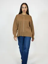 Buzo de tejido de punto en color camel, con cuello redondo y una línea vertical decorativa en color blanco que recorre el lado derecho del pecho. Presenta mangas largas con puños ajustados y un diseño de corte recto con aberturas laterales en el ruedo.