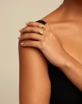 Anillo dorado con forma de hebilla central y efecto de clavo retorcido.