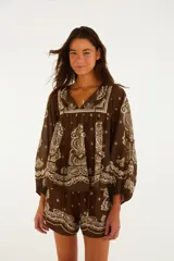 Blusa marrón de manga larga con estampado de estilo bandana en color crudo, escote en V con cordones y silueta amplia de corte bohemio.