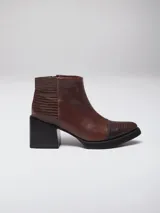 Botineta de cuero color suela, con diseño de punta fina y puntera texturizada con efecto reptil. Presenta una suela de madera clara con borde negro y cierre lateral interno.