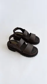 Sandalias de cuero con suela flatform track, tiras marrones y puntera con detalle de textura reptil en tono verde oliva. Cuenta con cierre de velcro en la tira trasera.