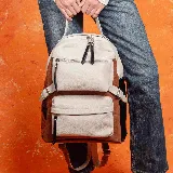 Mochila de cuero vacuno color tostado, blanco y negro. Tiene dos bolsillos frontales con cierre, un compartimento principal con cierre, un bolsillo interno con cierre, un bolsillo interno pequeño para el móvil y un bolsillo trasero externo con cierre.