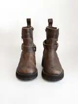 Bota corta de cuero vacuno en color chocolate con efecto desgastado. Presenta una suela track de goma negra, detalle de pulsera desmontable con tachas metálicas y cierre lateral.