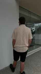 Camisa beige de crochet con cuello clásico y mangas cortas.