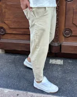 Pantalón jeans slouchy de color beige, con bolsillos laterales y corte relajado que se estrecha hacia los tobillos.