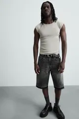 Bermuda de denim de algodón, color negro lavado, de corte ancho (baggy fit) y tiro medio. Presenta cinco bolsillos y bajo con acabado irregular deshilachado.