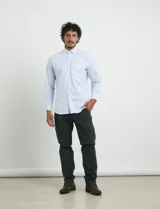 Camisa de manga larga con estampado de rayas verticales finas en color azul y blanco. Presenta cuello button-down, cierre frontal con botones nacarados y un bolsillo en el pecho.