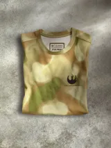 Remera de manga corta con estampado de camuflaje en tonos verdes y marrones, con logo de la Alianza Rebelde en el pecho y logo de Columbia en la manga. Cuenta con tecnología de protección solar.