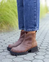 Botinetas de cuero color marrón con diseño combinado en cuero liso y gamuza. Presentan suela track de goma negra con taco cuadrado y tirador en la parte trasera.