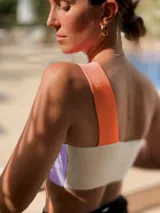 Top corto de tejido de punto, con diseño asimétrico de un solo hombro. La parte principal es de color lila y el tirante es de color naranja.