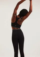 Calza deportiva de tiro alto confeccionada en tejido sin costuras, color negro, con ajuste ceñido al cuerpo y detalle de logo pequeño en tono contrastante sobre la pierna.