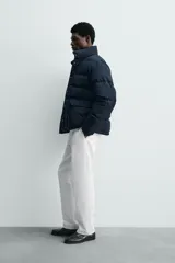 Campera puffer acolchada de corte regular fit, confeccionada en tejido técnico azul marino repelente al agua. Relleno interior de 80% plumón y 20% pluma. Cuenta con cuello subido, manga larga con puño elástico, bolsillos frontales de plastrón con solapa y cierre de cremallera oculta con solapa de botones a presión.