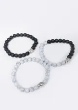 Set de tres pulseras elastizadas con cuentas de piedra natural y plástico, con dije de cabeza de Buda en aleación de metales.
