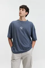 Remera de manga corta color azul oscuro, con corte holgado, hombros caídos y escote redondo. Presenta un logo bordado en blanco en el pecho.