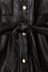 Chaqueta de efecto piel con cuello solapa, manga larga y cierre frontal con botones a presión. Presenta bolsillos delanteros con solapa y cinturón ajustable del mismo tejido para entallar la cintura.