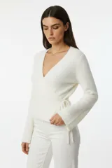 Saco de punto tipo wrap, color blanco, con escote en V, mangas largas y ajuste lateral mediante cordón.