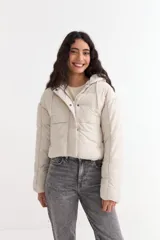 Campera puffer corta con capucha, cierre frontal y solapa con botones a presión. Diseño acolchado de corte holgado.