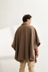 Poncho unisex de lana fina color marrón claro con cuello, cartera con broches a presión y bolsillo ojal. Diseño exclusivo de Don Baez, hecho 100% en Uruguay.