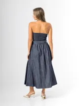 Vestido midi strapless de denim azul, con escote recto, espalda elastizada y falda amplia con pliegues. Incluye un cinto del mismo material con hebilla.