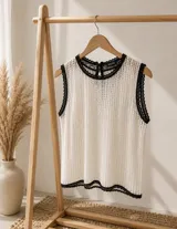 Blusa de punto calado color blanco con detalles de ribetes negros en cuello, sisas y ruedo.