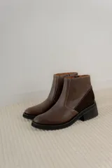 Bota corta de cuero marrón con panel trasero de gamuza en tono más oscuro, suela de goma negra y taco cuadrado bajo.