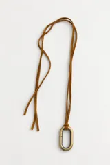 Collar largo con cordón de cuero tostado y dije metálico ovalado en tono dorado envejecido.