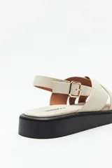 Sandalias color beige con capellada entrelazada y agarre ajustable en el talón. Plataforma de 3cm de alto y suela negra.