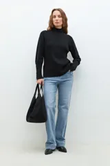 Polera negra de tejido de punto con cuello alto y mangas largas con cierre en los puños.