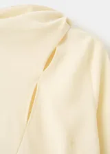 Blusa de manga larga en color crema, confeccionada en poliéster. Presenta un diseño de cuello alto con un sutil detalle de abertura frontal y corte recto.