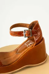 Sandalias de plataforma negra con diseño de puntera cuadrada, tira delantera fina y pulsera ajustable al tobillo con hebilla metálica. Presentan una textura tipo reptil en la parte posterior y una base de plataforma sólida.