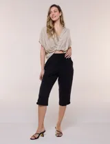 Pantalón capri negro de calce relajado y pierna recta, confeccionado en algodón. Posee cintura elastizada con cordón ajustable, bolsillos delanteros y detalle de presilla con botón en los ruedos.
