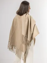 Ruana gris de tejido de punto con flecos en el ruedo.