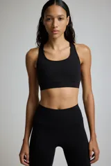 Top deportivo negro con espalda deportiva y soporte medio.