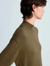 Vestido midi de punto fino en color verde oliva, con cuello alto tipo perkins, manga larga y diseño recto. Presenta un detalle de lazo anudado en la cintura y terminaciones en canalé.